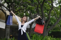 Woman with shopping bags, arms outstretched, smiling - Asia Images Group