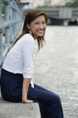 Woman sitting by river, smiling at camera - Asia Images Group