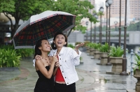 Two women standing under umbrella, smiling - Asia Images Group