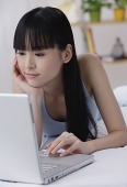 Young woman using laptop, hand on chin - Asia Images Group