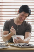 Man in kitchen stirring dough in mixing bowl - Asia Images Group