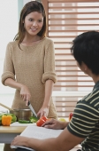 Woman chopping vegetables, looking at man in front of her - Asia Images Group