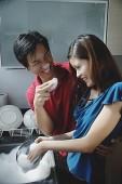 Couple washing dishes, playing with soap suds - Asia Images Group