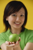 Young woman holding apple  in cupped hands - Asia Images Group