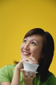Young woman holding teacup, looking away - Asia Images Group
