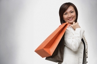 Businesswoman carrying shopping bags over shoulder, smiling - Asia Images Group