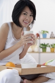 Young woman holding cup of coffee, smiling at camera - Asia Images Group