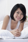 Young woman on bed, smiling at camera - Asia Images Group