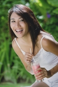 Young woman holding drink, smiling, looking at camera - Asia Images Group