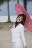 Young woman outdoors, using pink umbrella - Asia Images Group