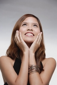 Woman smiling, hands on face, looking up - Asia Images Group
