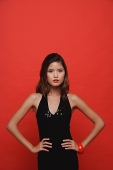 Woman in black dress standing against red background - Asia Images Group