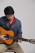 Man in denim jacket, playing guitar - Asia Images Group