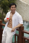 Man leaning on railing, holding cocktail - Asia Images Group