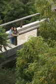 Couple standing on bridge, looking up - Asia Images Group
