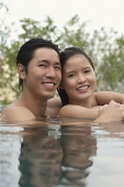 Couple in swimming pool, head above water, smiling at camera - Asia Images Group