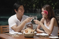 Couple sitting at outdoor table, toasting with glasses - Asia Images Group