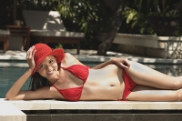 Woman in red bikini and hat, lying at the edge of swimming pool - Asia Images Group