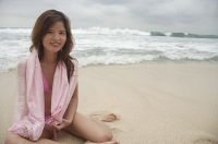 Woman sitting on beach, smiling at camera - Asia Images Group