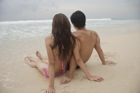 Couple sitting on beach, looking out to sea - Asia Images Group