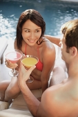 Couple by swimming pool, toasting with drinks - Asia Images Group