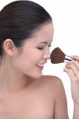 Young woman using make-up brush - Asia Images Group