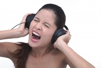 Young woman wearing headphones, screaming - Asia Images Group