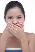 Young woman with hands over mouth, looking at camera - Asia Images Group