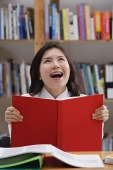 Young woman in library, looking up, smiling - Asia Images Group