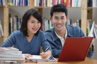 Couple studying in library, smiling at camera - Asia Images Group