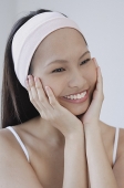 Young woman with hands on face, smiling - Asia Images Group