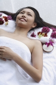 Young woman lying down on massage table, looking up - Asia Images Group