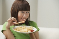 Young woman eating a plate of French fries - Asia Images Group