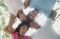 Young adults with arms around each other, looking down at camera - Asia Images Group