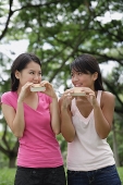 Two women eating ice cream, looking at each other - Asia Images Group