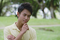 Young man with hand on chin - Asia Images Group