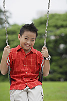 Boy on swing, smiling at camera - Asia Images Group