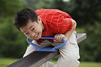 Boy sitting on See-Saw in playground - Asia Images Group