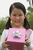 Girl holding pink wrapped gift box, smiling - Asia Images Group