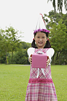 Girl with party hat holding pink gift box towards camera - Asia Images Group