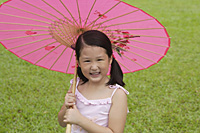 Girl using pink traditional Chinese paper umbrella, looking at camera - Asia Images Group