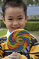Boy holding colourful lollipop - Asia Images Group