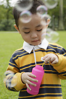Boy with bubble wand, bubbles around him - Asia Images Group