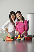 Mother and adult daughter in kitchen, looking at camera - Asia Images Group