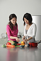 Mother guiding daughter in preparing a meal - Asia Images Group