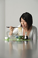 Young woman eating a bowl of noodles - Asia Images Group