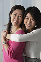 Mother with grown daughter, embracing, looking at camera - Asia Images Group