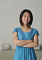 Young woman in blue dress, arms crossed, smiling at camera - Asia Images Group