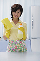Woman in kitchen, holding cleaning detergent and sponge - Asia Images Group