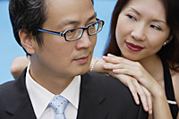 Businessman with head turned, woman leaning on his shoulder - Asia Images Group